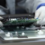 Technician handling a circuit board on a production line