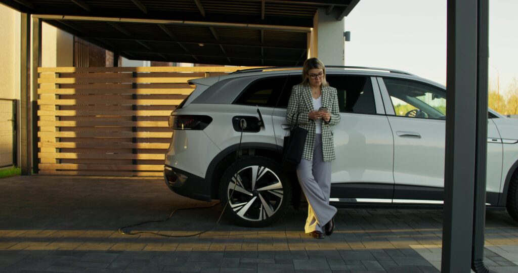 Driver using a phone app next to a charging electric car