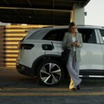 Driver using a phone app next to a charging electric car