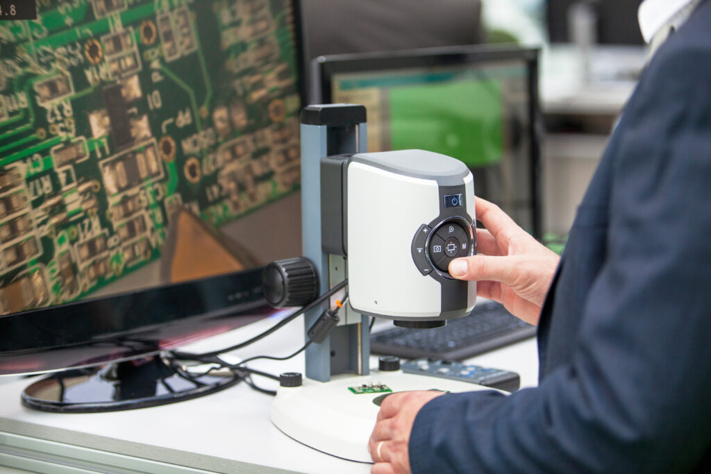 Electronics engineer inspecting printed circuit board PCB wi