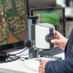 Electronics engineer inspecting printed circuit board PCB wi