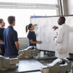 Engineer and female apprentice presenting at whiteboard