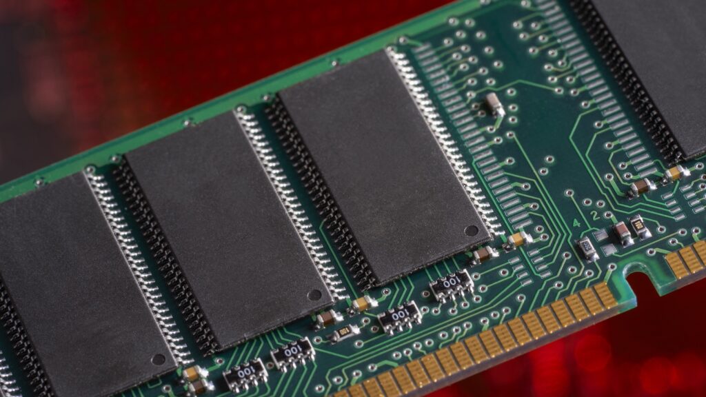 Close-up of a memory module: DRAM chips and gold contacts on a green circuit board